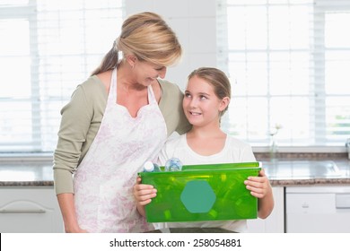 Daughter holding recycling box with her mother at home in the kitchen - Powered by Shutterstock