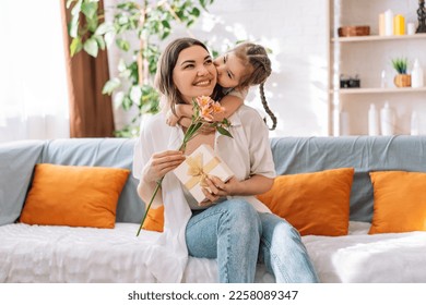 Daughter hugged her mother and gave a gift and flowers. mother's day