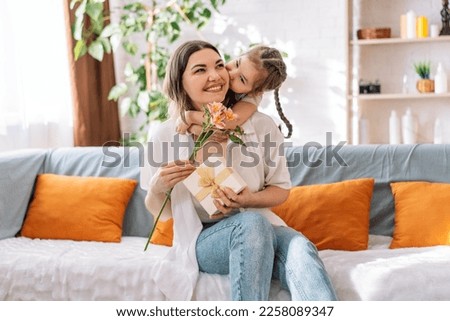 Daughter hugged her mother and gave a gift and flowers. mother's day