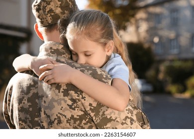 Daughter hugging her father in Ukrainian military uniform outdoors. Family reunion - Powered by Shutterstock