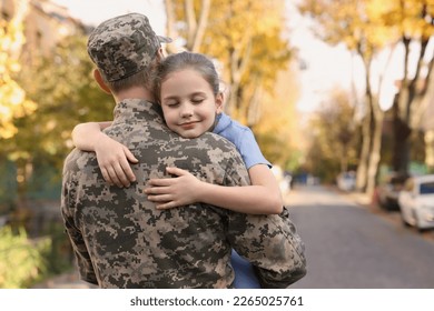 Daughter hugging her father in Ukrainian military uniform on city street. Family reunion - Powered by Shutterstock