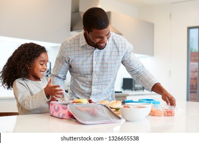 Daughter In Kitchen At Home Helping Father To Make Healthy Packed Lunch - Powered by Shutterstock