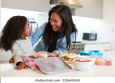 Daughter In Kitchen At Home Helping Mother To Make Healthy Packed Lunch