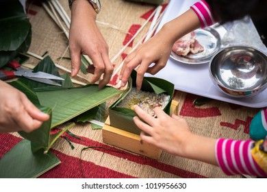 The daughter learning to make Chung cake by hands with his father closeup, Chung cake is the most important traditional Vietnamese lunar New Year (Tet) food.