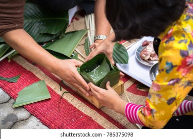 The daughter learning to make Chung cake by hands with his father closeup, Chung cake is the most important traditional Vietnamese lunar New Year (Tet) food.