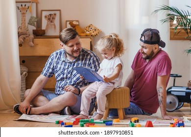 Daughter learning to read a book with her gay dads. Family's wonderful bonding moments.
