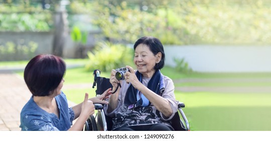 Daughter Looking After Elderly Mother In Backyard