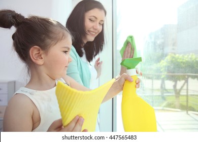 Daughter and mother cleaning window together