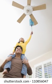 Daughter On Father's Shoulder Cleaning Fan