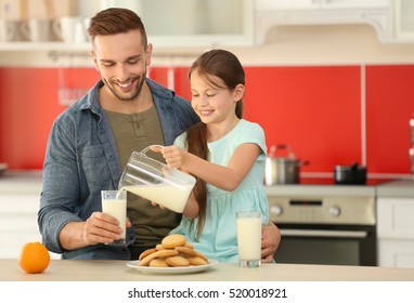 Daughter pouring fresh milk into glass for father at kitchen - Powered by Shutterstock