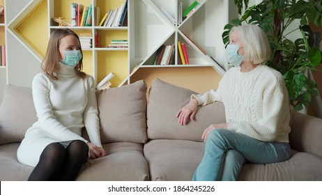 Daughter And Senior Mother Wearing Medical Masks Having Fun Talk At Home, Elderly Millennial Women Of Two Age Generation Enjoy Conversation