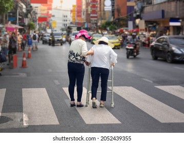 Daughter take care elderly woman crossing the street in Chinatown area