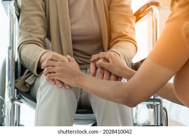 daughter Take care sitting and touch hand mother elderly Caucasian disability on wheelchair depressed for encouragement. Young women helping to service senior retire at nursing home. Selective focus.