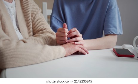 Daughter Visiting Elderly Mother. They Sit At The Table And Talk About Serious Things