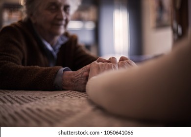 Daughter visiting her mother,holding hands. - Shutterstock ID 1050641066