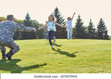 Daughters are running to their soldier father. Reunion of happy family on the meadow. - Powered by Shutterstock