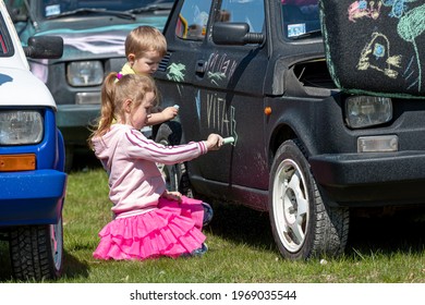 Daugmale, Latvia - May 01, 2021: children draw with crayons on a vintage car Fiat 126