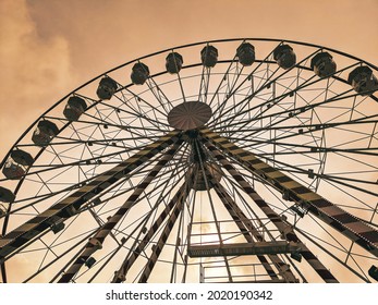 Daunting view looking up at a Ferris wheel in the sunset.
