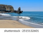 Davenport beach, Santa Cruz, California on a sunny day.. Roch formations and ocean wave in an S curve