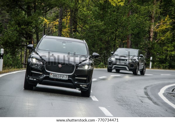 DAVOS, SWITZERLAND - OCTOBER 3, 2017: Jaguar\
F-Pace and Range Rover Evoque made a long way to a mountain pass\
Umbrail in Switzerland. Photo taken on the serpentine road in the\
Alps near Davos.