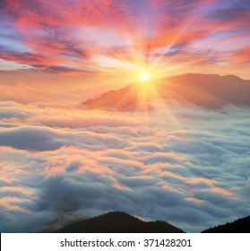 At dawn, after a warm rain ridges Chornogory haze enveloped with rays of sunshine. Sea fog in the pink light is very beautiful and fabulous, picturesque vague wave rolled on the slopes of the peaks - Powered by Shutterstock