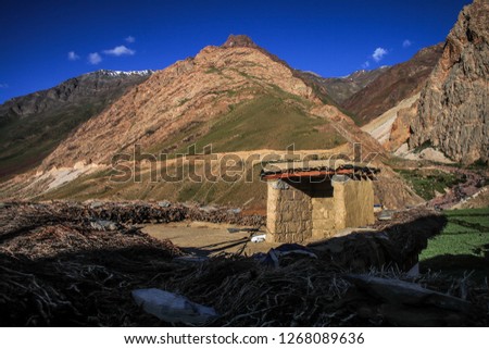 Dawn breaks as the full moon sets over Mudh village in Pin River Valley, Himachal Pradesh / India: A cold desolate desert mountain valley located very high in the rain shadow region of the himalayas.