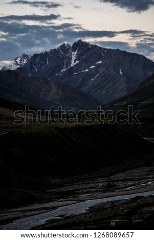 Dawn breaks as the full moon sets over Mudh village in Pin River Valley, Himachal Pradesh / India: A cold desolate desert mountain valley located very high in the rain shadow region of the himalayas.