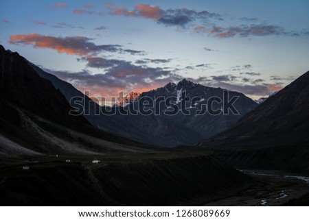 Dawn breaks as the full moon sets over Mudh village in Pin River Valley, Himachal Pradesh / India: A cold desolate desert mountain valley located very high in the rain shadow region of the himalayas.