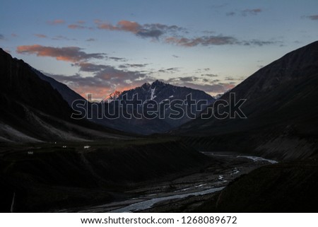 Dawn breaks as the full moon sets over Mudh village in Pin River Valley, Himachal Pradesh / India: A cold desolate desert mountain valley located very high in the rain shadow region of the himalayas.