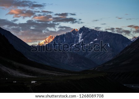 Dawn breaks as the full moon sets over Mudh village in Pin River Valley, Himachal Pradesh / India: A cold desolate desert mountain valley located very high in the rain shadow region of the himalayas.