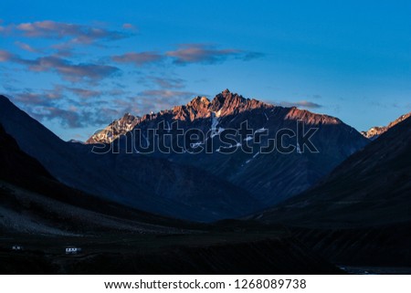 Dawn breaks as the full moon sets over Mudh village in Pin River Valley, Himachal Pradesh / India: A cold desolate desert mountain valley located very high in the rain shadow region of the himalayas.