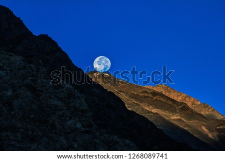 Dawn breaks as the full moon sets over Mudh village in Pin River Valley, Himachal Pradesh / India: A cold desolate desert mountain valley located very high in the rain shadow region of the himalayas.