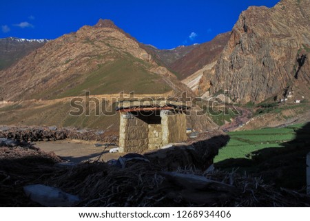Dawn breaks as the full moon sets over Mudh village in Pin River Valley, Himachal Pradesh / India: A cold desolate desert mountain valley located very high in the rain shadow region of the himalayas.