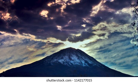 dawn of a conical volcano with a shadow of clouds that seems to be another volcano