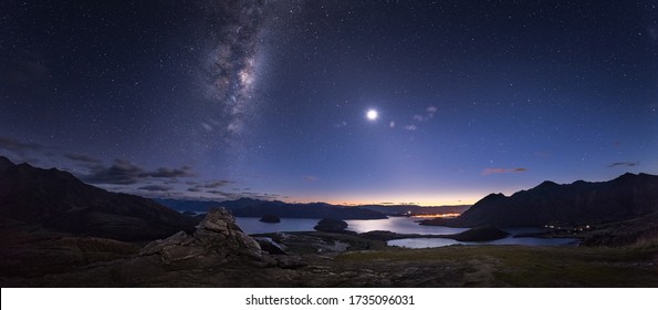 Dawn at Lake Wanaka in New Zealand under the milky way in a stary sky with a rising full moon.  - Shutterstock ID 1735096031