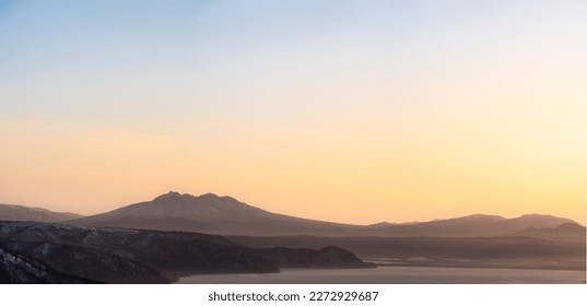 The dawn sky in a pale gradation and the silhouettes of mountains in the distance.