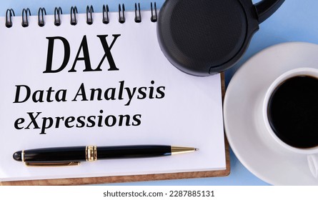 DAX (Data Analysis eXpressions) - words in a white notepad on a light background with a cup of coffee and headphones