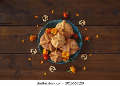 Day Of The Dead, Dia De Los Muertos Celebration Party Background With Bread Of Death Or Pan De Muerto, Skulls, Marigolds Flowers On Dark Wood Table With Copy Space. Traditional Mexican Culture 