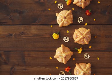 Day Of The Dead, Dia De Los Muertos Celebration Party Background With Bread Of Death Or Pan De Muerto, Skulls, Marigolds Flowers On Dark Wood Table With Copy Space. Traditional Mexican Culture 