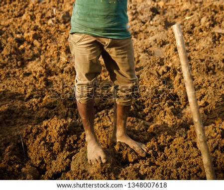A day labour standing on a soil surface in the afternoon