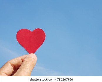 Valentine’s Day. Love Concept. Hand Holding Paper Heart On Blue Sky Background. Copy Space