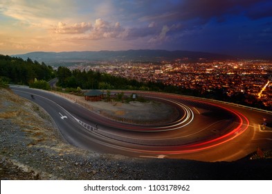 Day And Night. Light Streaks Over Road And Skopje City In Distance, Macedonia. Photo Manipulation.