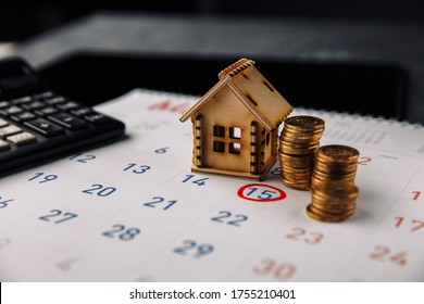Day to pay for mortgage, buying new house planning or real estate and property reminder concept. Wooden house on white calendar with calculator and coins
