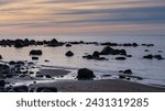 As day transitions into night, Veczemju Klintis offers a glimpse of coastal magic, with the rocky beach coast bathed in the ethereal light of twilight during sunset