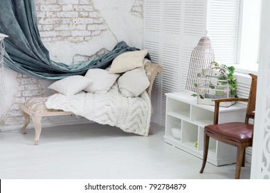 daybed with cushions in a corner of the room with gray . wall of white brick. interior. white room. white fireplace