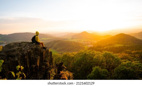 Daybreak moment. Squating hiker Tall hiker in mountains. Thinking man silhouette in nature within daybreak. The vignetting effect.