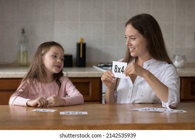 Daycare teacher and little kid girl learning math, working with multiplication table, using flash cards, playing educational game. Mom helping daughter kid with mathematic school task