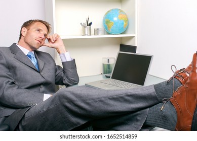 Daydreaming Businessman Kicking Back At His Desk In A White Office Cubicle