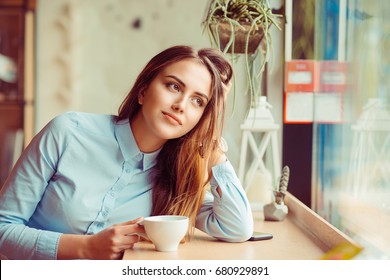 Daydreaming on a coffee break. Pensive happy woman remembering looking at side up sitting in a bar, coffee shop drinking tea