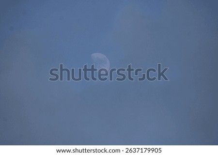 Daylight moon though the clouds